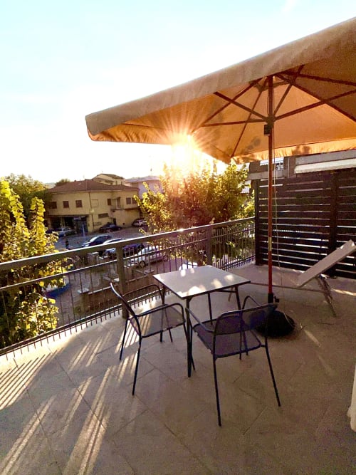 Terrazza privata dell'Hotel Il Mulino con vista al tramonto, tavolo, sedie e ombrellone che si affacciano sulla corte di Casalgrande