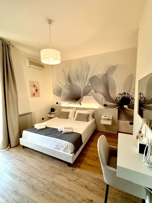Camera da letto di lusso moderna all'Hotel Il Mulino con grande opera d'arte floreale, letto bianco, pavimenti in legno e arredamenti contemporanei