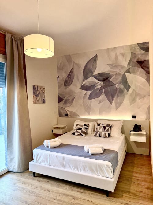 Camera deluxe all'Hotel Il Mulino con arte botanica a parete, lampada a sospensione, biancheria bianca, cuscini decorati e privata