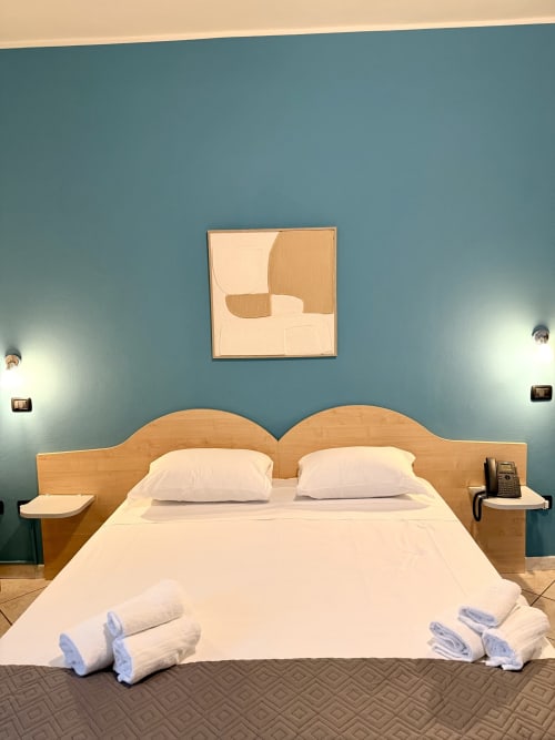 Camera moderna dell'Hotel Il Mulino con pareti blu, letto in legno, cuscini e asciugamani bianchi, arredamento contemporaneo