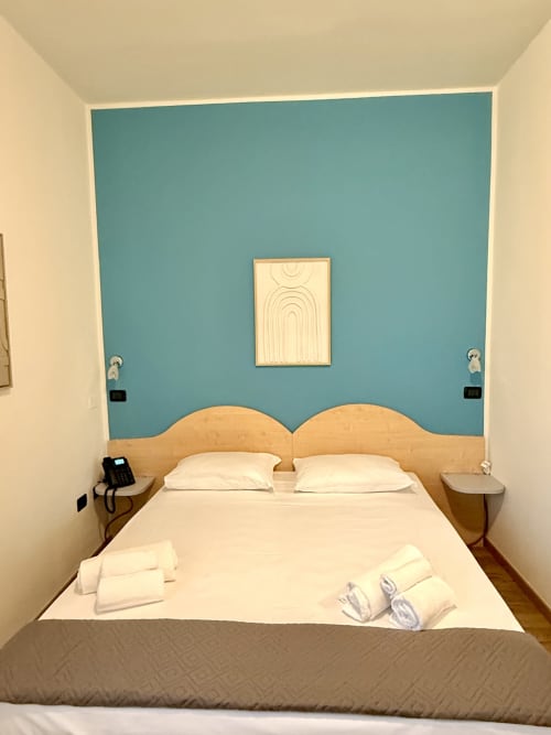 Camera doppia standard dell'Hotel Il Mulino con parete azzurra, testata in legno, biancheria bianca e comfort moderni