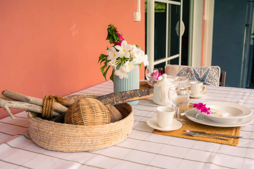 Table de balcon bord de mer dressée avec fleurs, couverts et panier tressé au Nid De Bellemont, Trois-Rivières