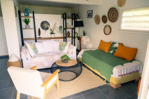 Chambre lumineuse du Nid De Bellemont avec lits jumeaux, plantes tropicales, paniers tissés et décor côtier