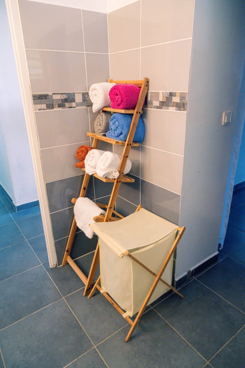 Porte-serviettes en bois avec serviettes colorées pliées et panier à linge dans la salle de bain cottage du Nid De Bellemont, Trois-Rivières