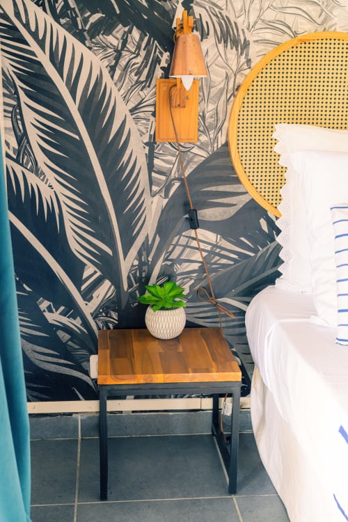 Chambre chaleureuse avec table de nuit en bois, succulente en pot, suspension orange et papier peint tropical chez Le Nid De