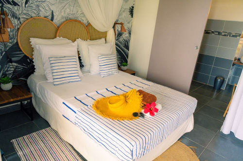 Chambre avec literie rayée, canard décoratif jaune et tête de lit en rotin au gîte Fwégate de Le Nid De Bellemont
