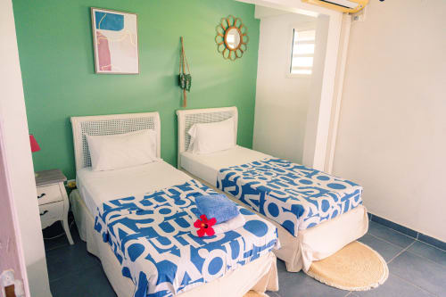 Chambre twin lumineuse au gîte Le Nid De Bellemont à Trois-Rivières, aux murs verts, linge de lit à motifs bleus et style côtier