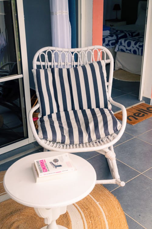 Chaise en rotin blanc avec coussin rayé bleu marine et petite table ronde au gîte Le Nid De Bellemont à Trois-Rivières