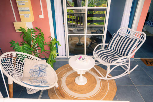 Terrasse vue mer du gîte Le Nid De Bellemont avec chaises en rotin blanc, petite table et plantes tropicales à Trois-Rivières
