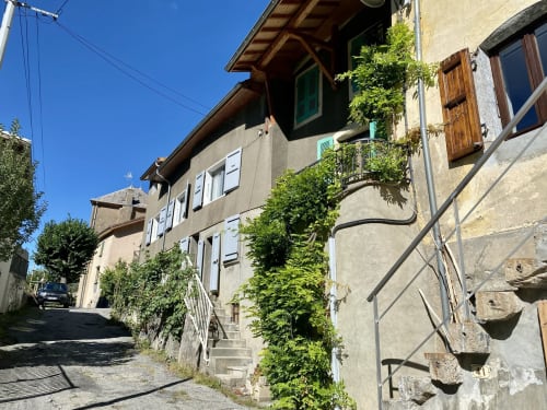 Entrée de l'Hôtel le Tilleul à Corps, France avec façade en pierre couverte de lierre et volets en bois