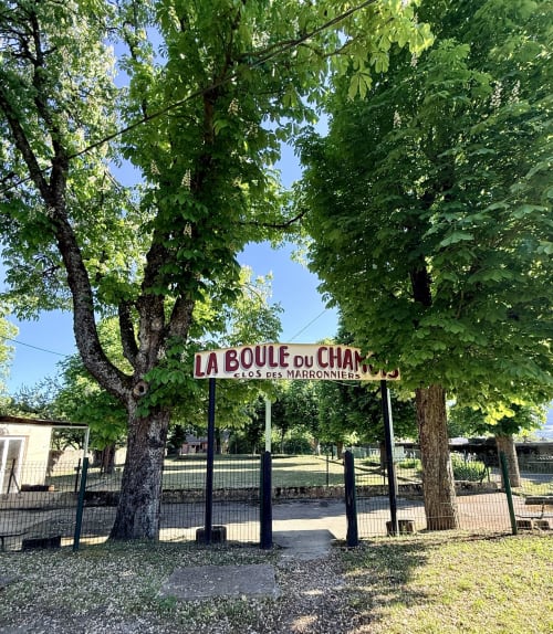 Enseigne vintage « La Boule du Champ » encadrée par des arbres verdoyants à l'Hôtel le tilleul à Corps, France