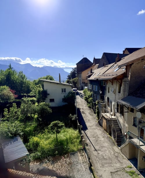 Hôtel le tilleul à Corps, France : rue pittoresque d'un village alpin avec bâtiments en pierre traditionnels et montagnes en arrière-plan