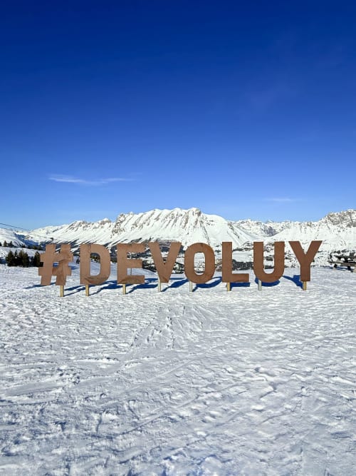 Panneau #DEVOLUY dans un paysage enneigé avec montagnes aux sommets couverts de neige, Corps, Alpes françaises