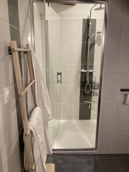 Salle de bains moderne de l'hôtel Le relais de Touraine à Abilly avec cabine de douche vitrée, pommeau de douche pluie et sèche-serviettes électrique