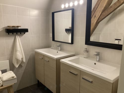 Salle de bains moderne au Relais de Touraine avec doubles vasques, miroirs encadrés foncés, meuble en bois et carrelage blanc.