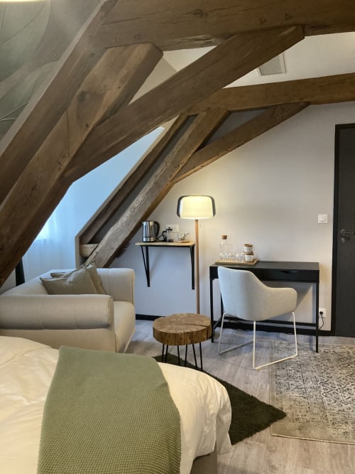 Chambre mansardée moderne au Relais de Touraine avec poutres apparentes, mobilier crème, bureau en bois et vue sur la ville