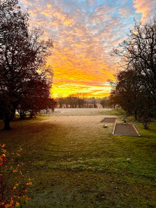 Vue au coucher de soleil du Domaine de La Briandais à Missillac, avec terrains de cornhole surplombant un lac paisible