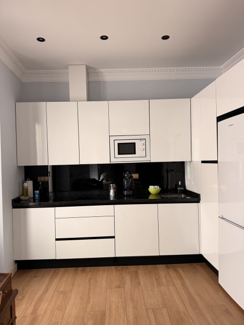 Cocina moderna blanca con encimera negra en Suite Giraldillo, apartamento hotel de Sevilla