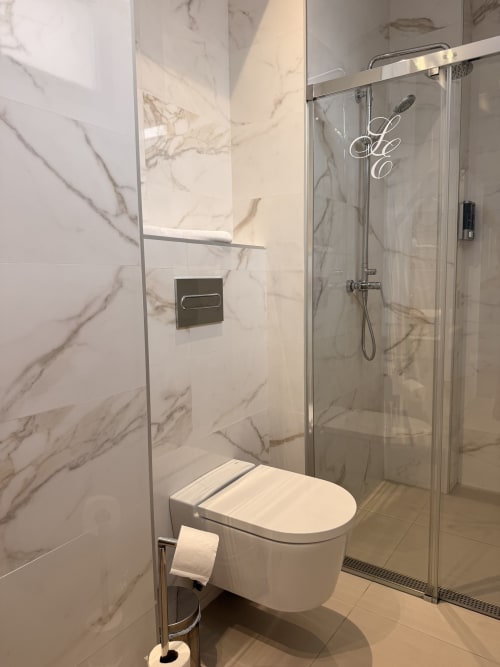 Baño moderno en Suite Giraldillo, hotel Sevilla, con ducha de mármol y inodoro mural
