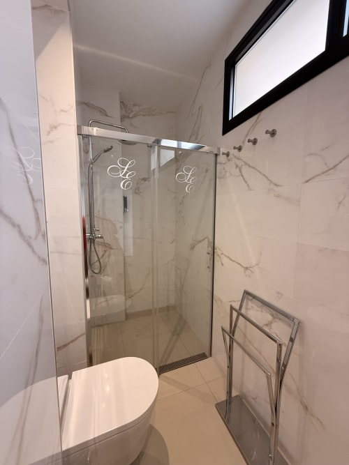 Baño moderno en Edificio San Esteban 16, Sevilla, con paredes de mármol, ducha de cristal, inodoro y toallero climatizado