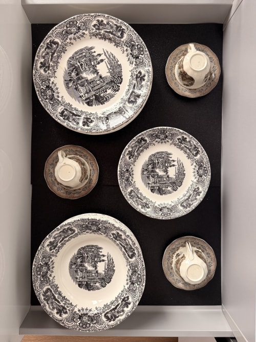 Elegante vajilla de porcelana blanca y negra con motivos ornamentales exhibida en la Suite Giraldillo del hotel Sevilla