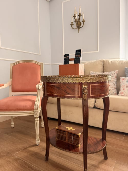 Elegante sala de estar en suite de hotel sevillano con mesa redonda de madera, butaca coral y sofá beige