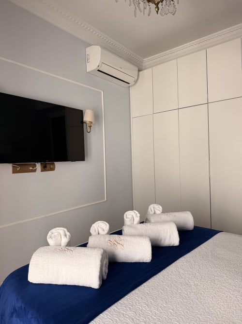 Habitación Giraldillo Suite en hotel de Sevilla con toallas enrolladas en cama azul, TV mural, aire acondicionado y armario color crema