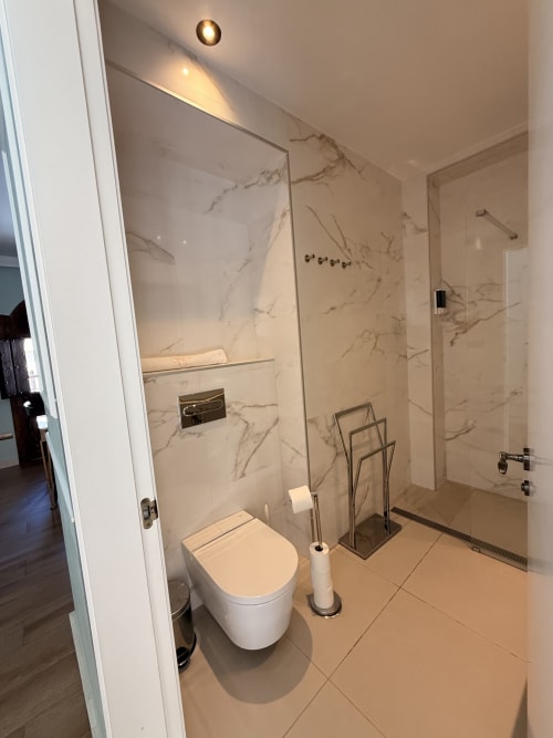Baño moderno en Edificio San Esteban 16 Sevilla con paredes de azulejos efecto mármol, inodoro blanco, ducha con mamparas de cristal y