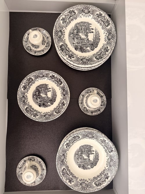Juego de vajilla de porcelana decorativa en blanco y negro con patrones ornamentales y motivos centrales, exhibido en suite del hotel de Sevilla