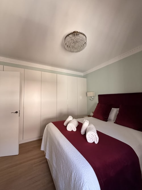 Dormitorio moderno en Edificio San Esteban 16 de Sevilla con cama burdeos, almohadas blancas, armario empotrado y techo elegante