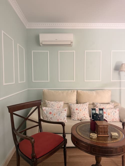 Sala de estar de la Suite Julio César en hotel de Sevilla con sofá crema, cojines florales, muebles de madera y aire acondicionado