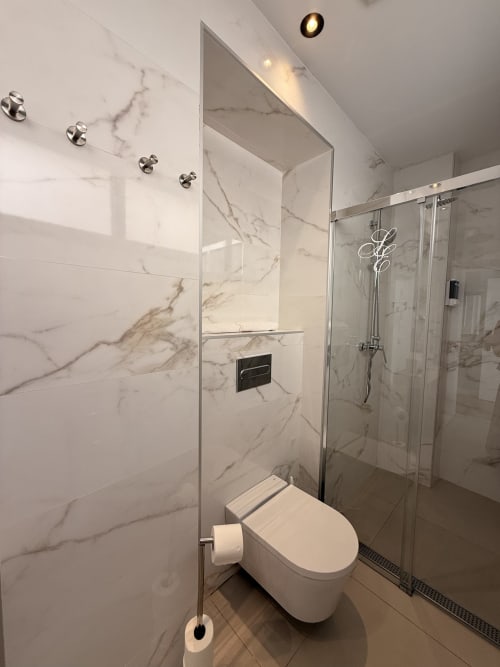 Baño moderno con mármol y ducha con cerramiento de cristal en la suite del apartamento Edificio San Esteban 16, Sevilla
