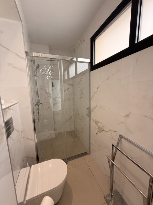 Baño moderno en Edificio San Esteban, Sevilla con cabina de ducha de mármol, inodoro blanco y accesorios contemporáneos