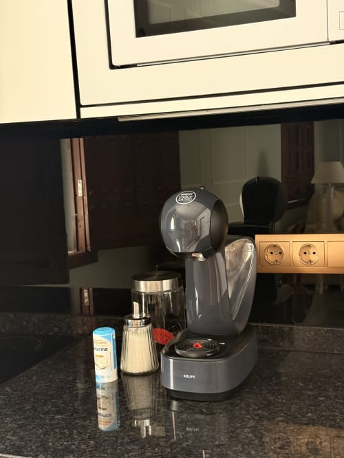 Cafetera Krups con molinillo y vaporizador de leche sobre encimera oscura en apartamento de Sevilla