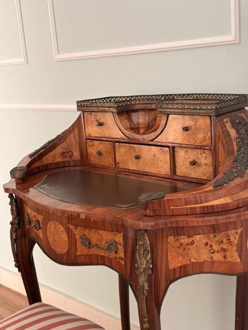 Escritorio de madera ornamentado con incrustaciones de chapa nudosa y herrajes de bronce en suite de hotel de Sevilla