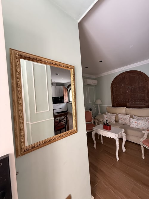 Elegante suite en Edificio San Esteban 16, Sevilla, con espejo ornamental, muebles color crema y suelo de madera oscura
