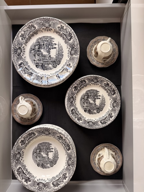 Elegante juego de vajilla porcelana blanca y negra exhibido en suite del hotel Sevilla, con platos y tazas ornamentados