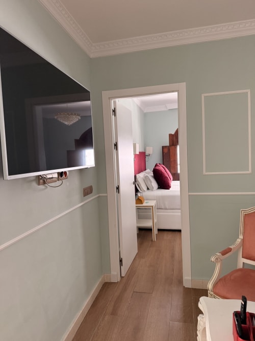 Pasillo de la Suite Mañara en Edificio San Esteban 16, Sevilla, que conduce al dormitorio con puertas blancas y paredes verde salvia