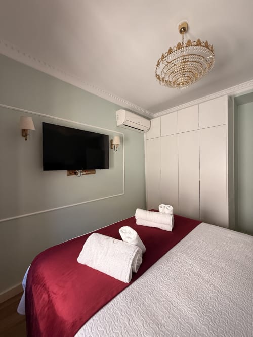 Dormitorio moderno en Edificio San Esteban 16, Sevilla con cama roja, TV mural, lámpara decorativa y armario blanco