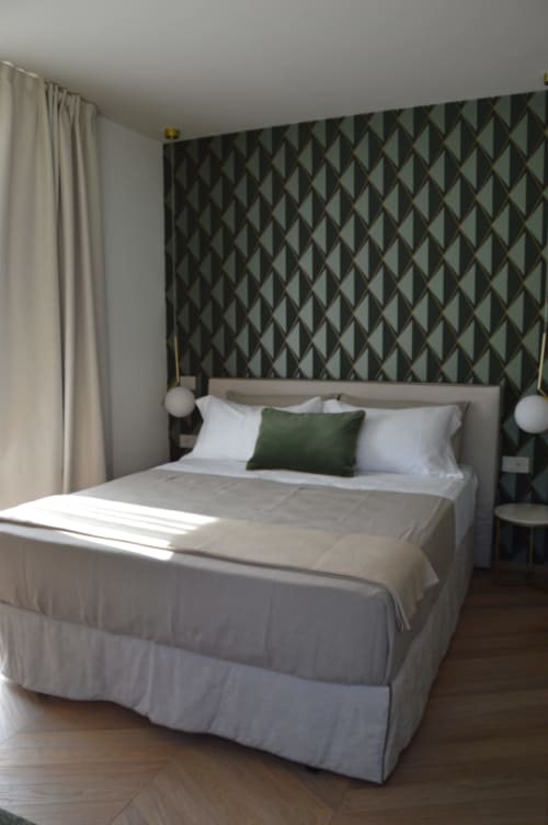 Camera moderna di Villa Rosati con parete accent geometrica, biancheria neutra, cuscino verde e tende color crema