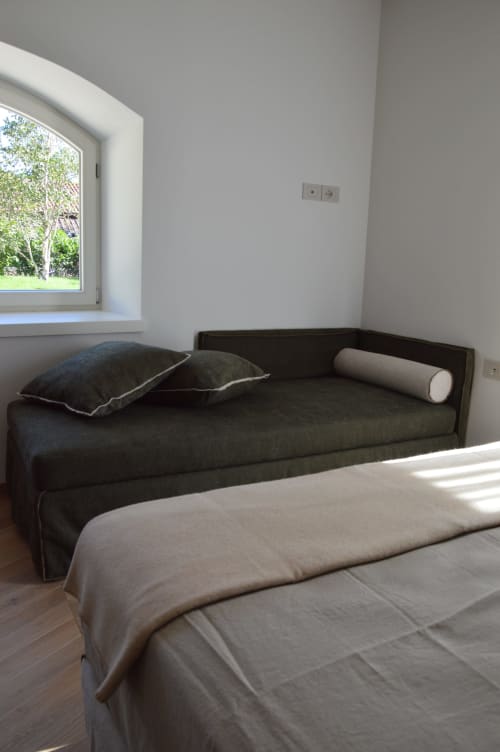 Camera moderna di Villa Rosati con divano scuro, letto e finestra con vista sul giardino a Sanzeno