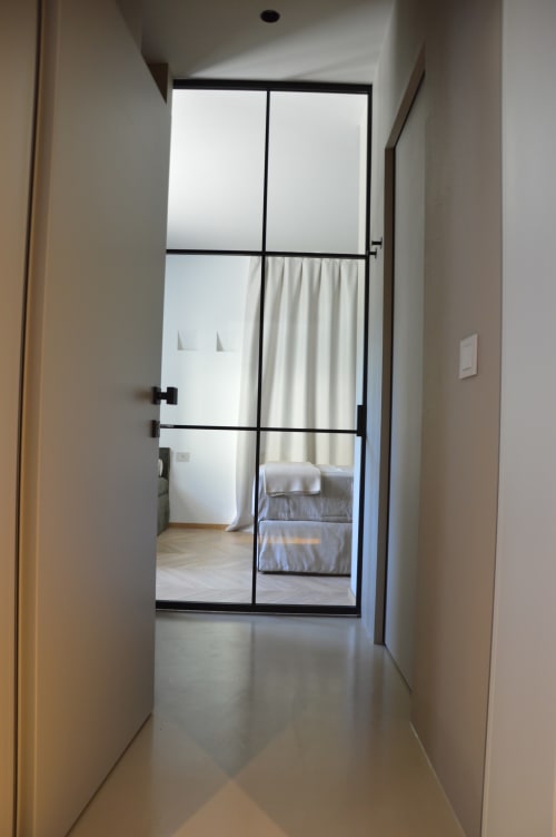 Moderno corridoio con porta vetrata incorniciata in nero che conduce alla camera da letto, Villa Rosati boutique hotel, Sanzeno
