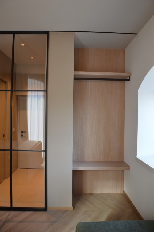 Camera da letto moderna con guardaroba e zona storage a Villa Rosati, con mobili in legno e porta in vetro a Sanzeno, Italia