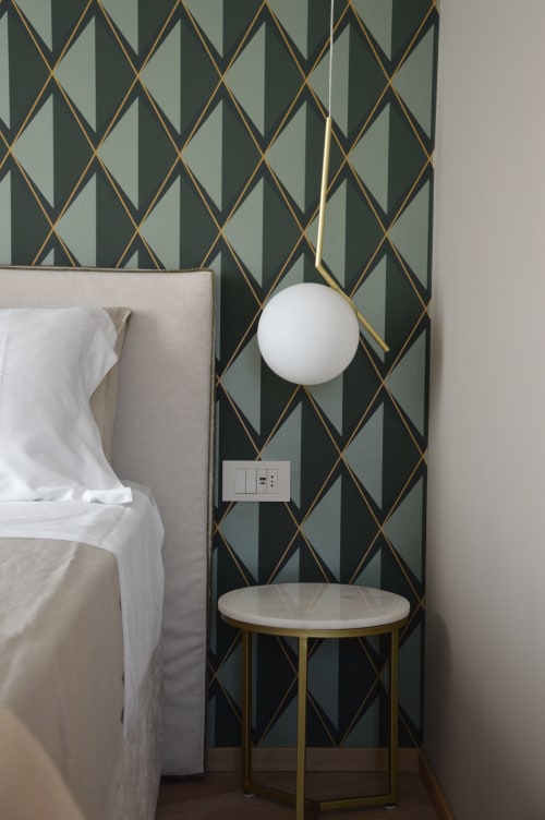 Camera da letto moderna a Villa Rosati con carta da parati a motivi geometrici, letto beige, lampada a sospensione bianca e tavolino rotondo in marmo