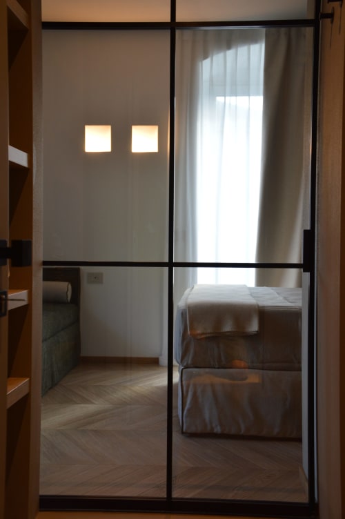 Porte scorrevoli in vetro con due finestre affacciate sul letto della camera Muschio a Villa Rosati, una struttura con vista giardino