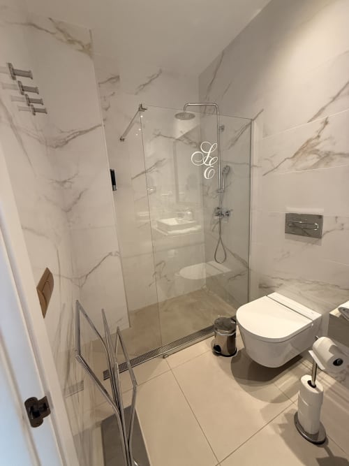 Baño moderno en la Suite 1A Monardes del Edificio San Esteban 16, Sevilla, con paredes de mármol y ducha de cristal
