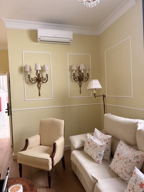 Elegante sala de estar de la suite en Edificio San Esteban 16 de Sevilla con sillón crema, sofá, apliques decorativos