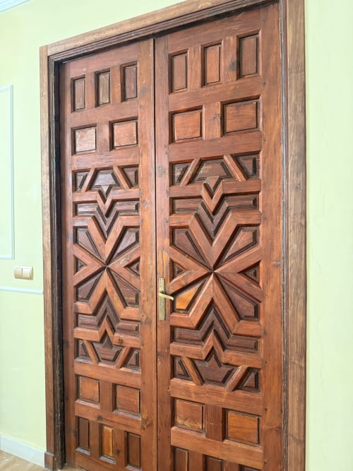 Puertas dobles de madera ornamentada con patrones geométricos tallados en el Edificio San Esteban 16 de Sevilla