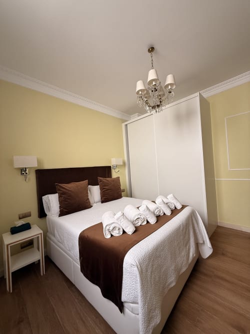 Suite elegante en Edificio San Esteban 16, Sevilla con paredes amarillas, cama marrón y toallas blancas