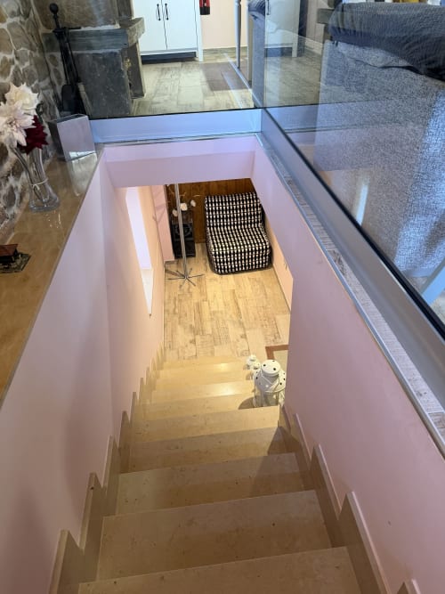 Escalera con paredes rosa bajando hacia piso de madera en habitación de hotel rural, Asturias